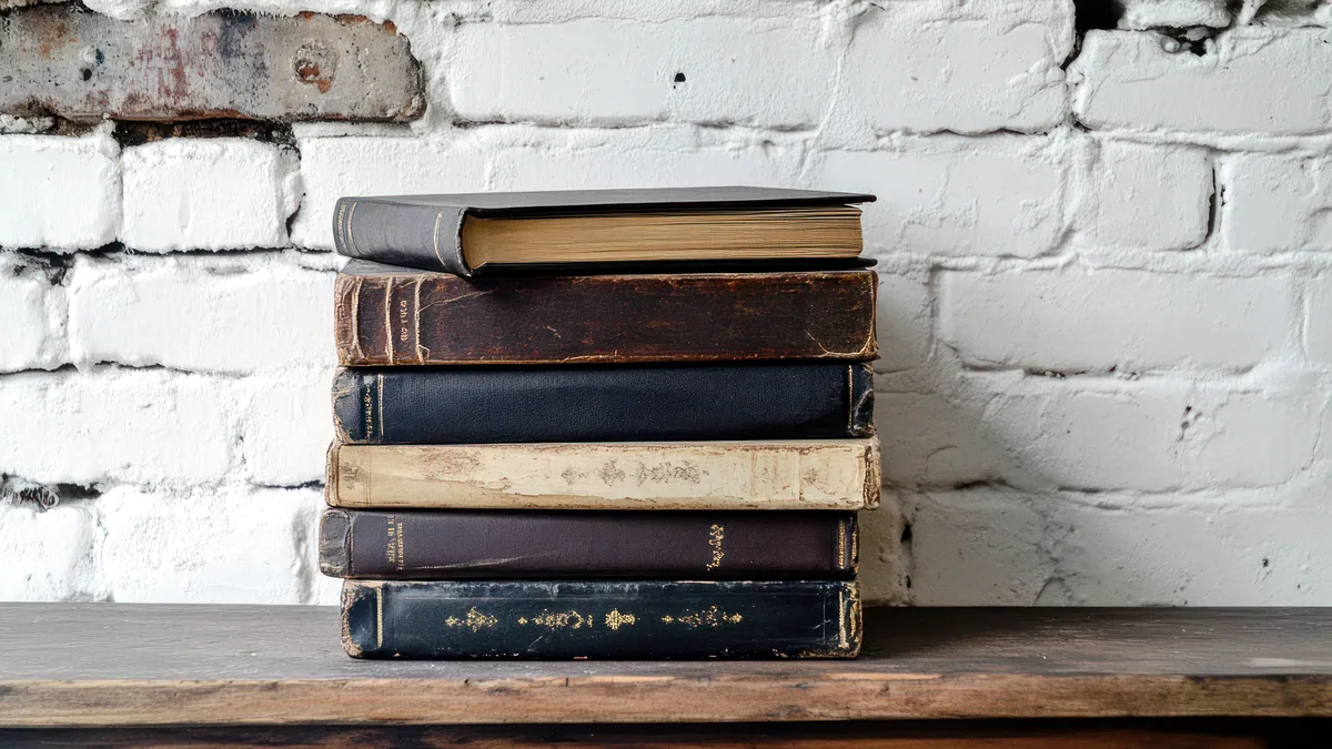 Spines of classic philosophy books lined up on a worn wooden shelf.